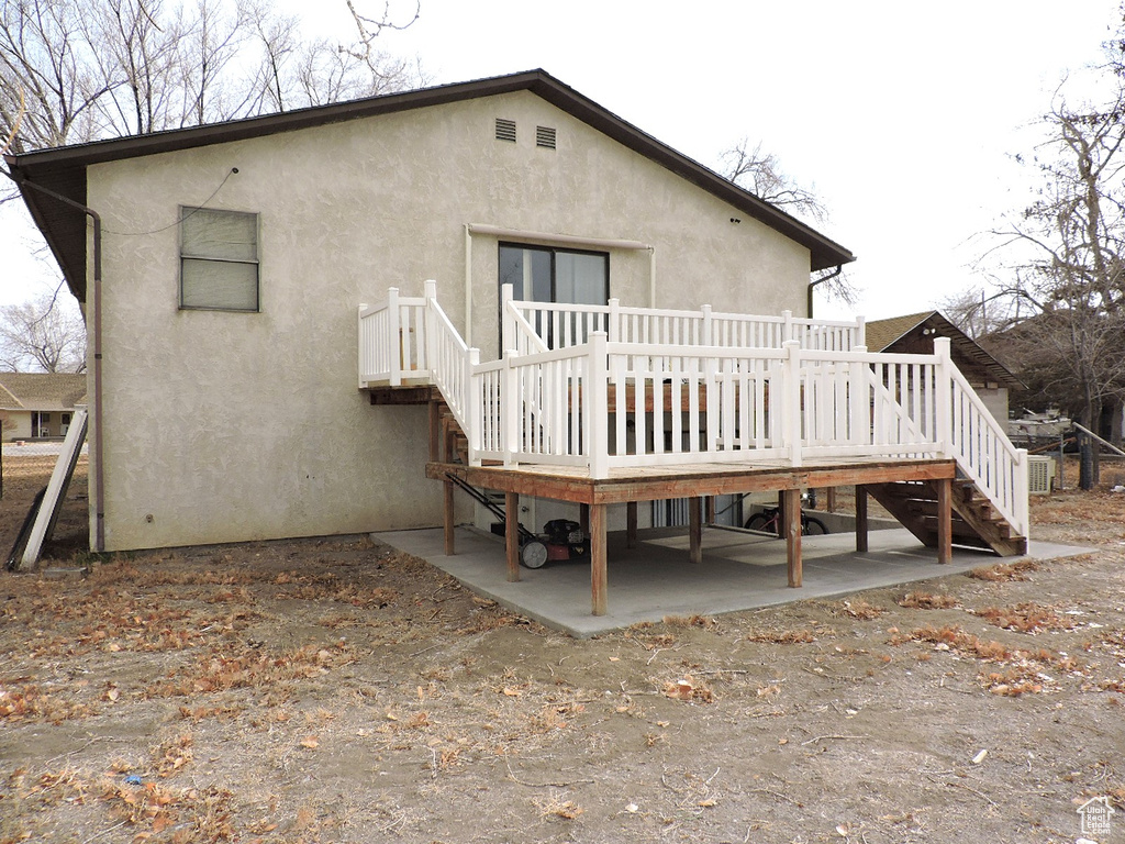Back of property with a wooden deck and a patio