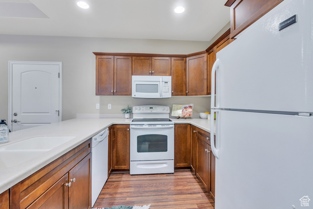 Kitchen with sink, white appliances, and light hardwood / wood-style flooring