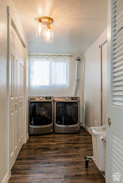Laundry room with dark wood-type flooring, a chandelier, and washer and dryer