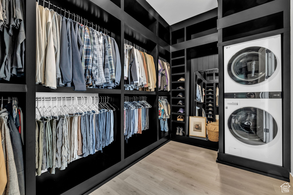 Spacious closet with light wood-type flooring and stacked washing maching and dryer