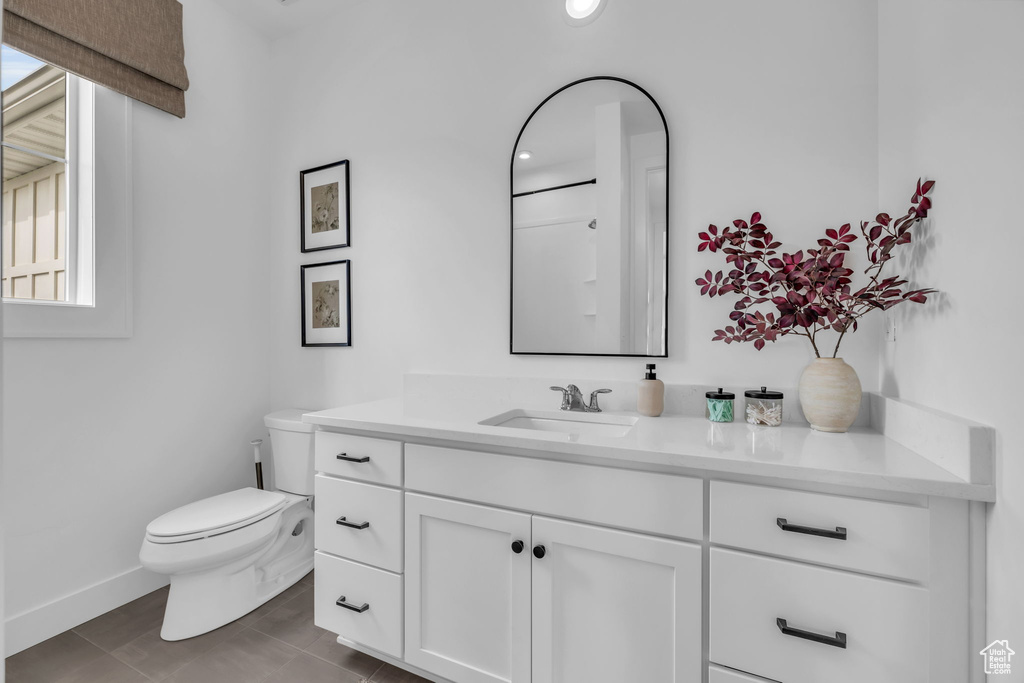 Bathroom with tile floors, vanity, a healthy amount of sunlight, and toilet