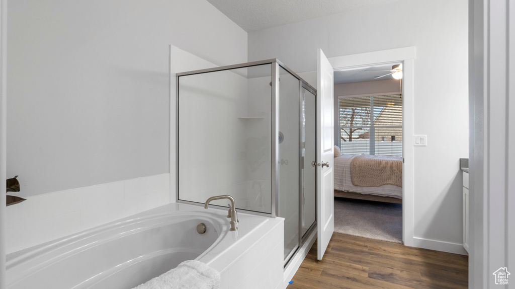 Bathroom featuring hardwood / wood-style floors, ceiling fan, and plus walk in shower