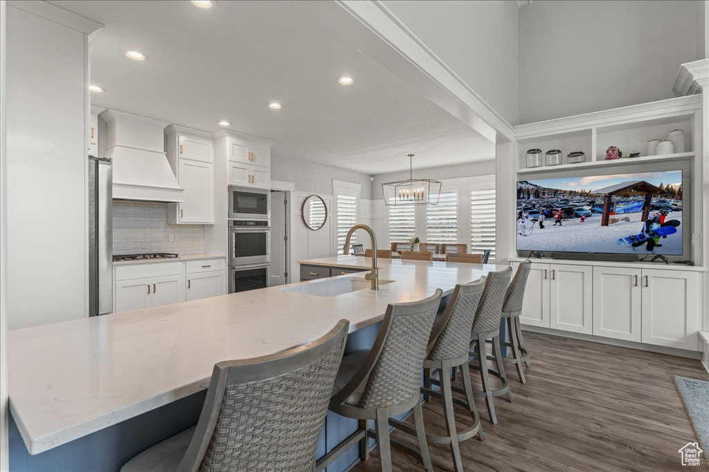 Kitchen with pendant lighting, dark hardwood / wood-style flooring, custom range hood, a notable chandelier, and appliances with stainless steel finishes