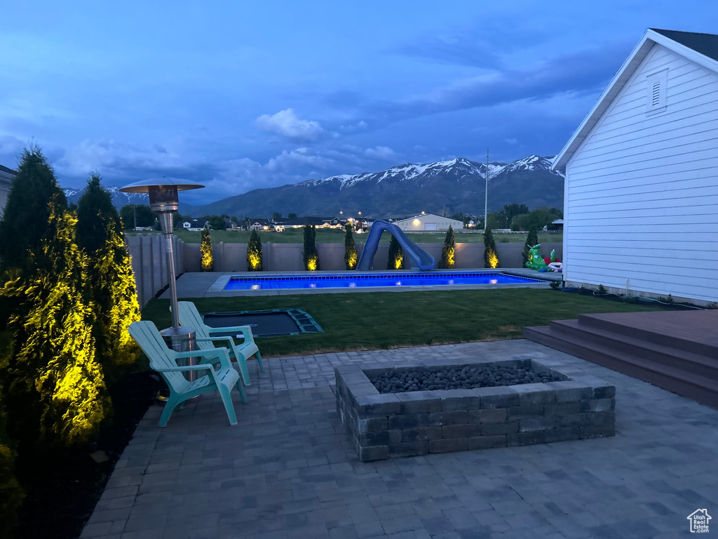 View of terrace with a fire pit, a fenced in pool, and a mountain view