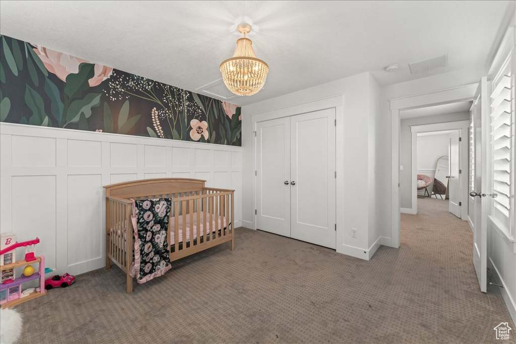 Carpeted bedroom with a chandelier, a nursery area, and a closet