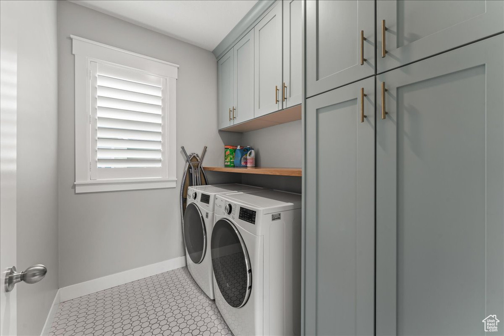 Laundry room featuring separate washer and dryer, cabinets, and light tile floors