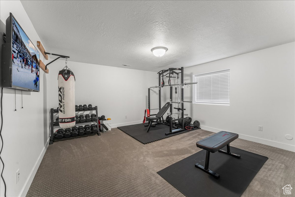 Exercise room featuring dark carpet and a textured ceiling