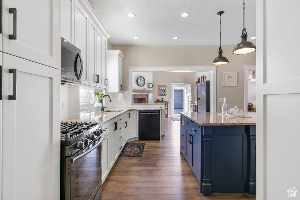 Kitchen featuring dark hardwood / wood-style flooring, blue cabinetry, range with gas stovetop, decorative light fixtures, and dishwasher