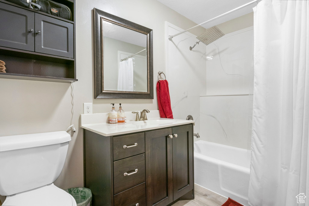 Full bathroom featuring hardwood / wood-style floors, toilet, shower / tub combo, and vanity