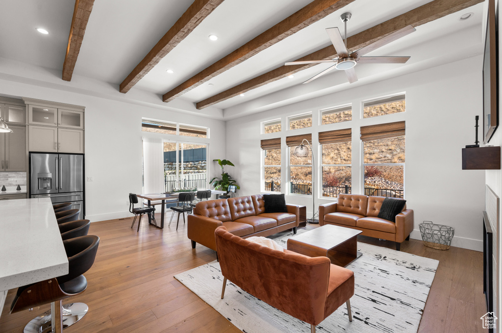 Living room with light hardwood / wood-style flooring, beam ceiling, and ceiling fan