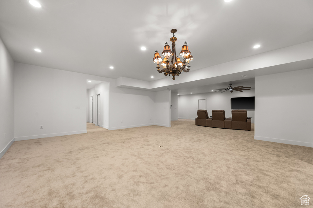 Unfurnished living room featuring ceiling fan with notable chandelier and light carpet