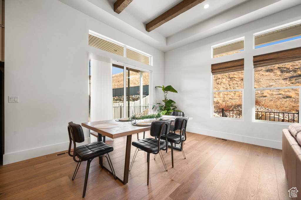 Dining space with light hardwood / wood-style flooring and beam ceiling