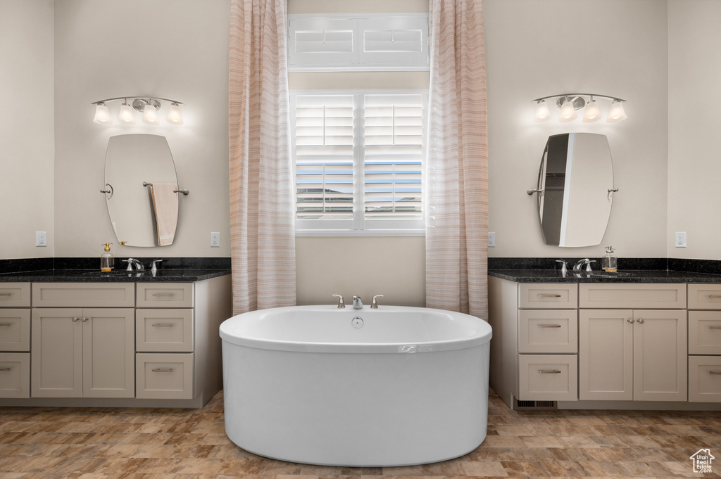 Bathroom featuring a bath, tile flooring, and dual bowl vanity
