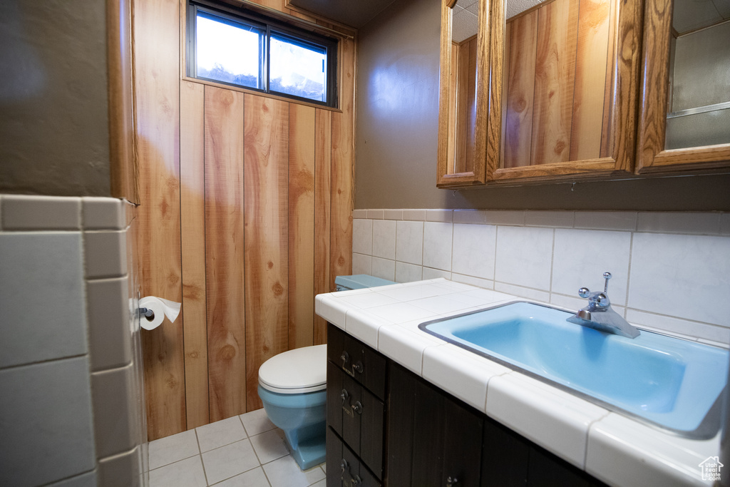 Bathroom with tile floors, tasteful backsplash, toilet, and vanity with extensive cabinet space