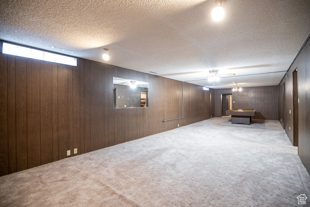 Basement featuring wood walls, pool table, and a textured ceiling