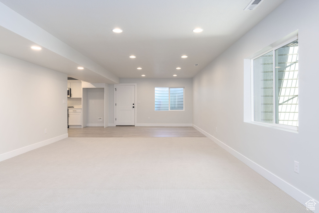 Unfurnished living room with light colored carpet and a healthy amount of sunlight