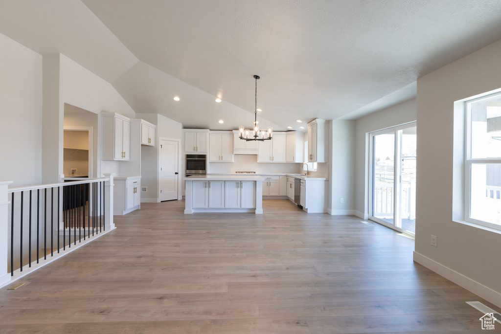 Kitchen featuring a notable chandelier, light hardwood / wood-style flooring, stainless steel appliances, white cabinets, and a kitchen island