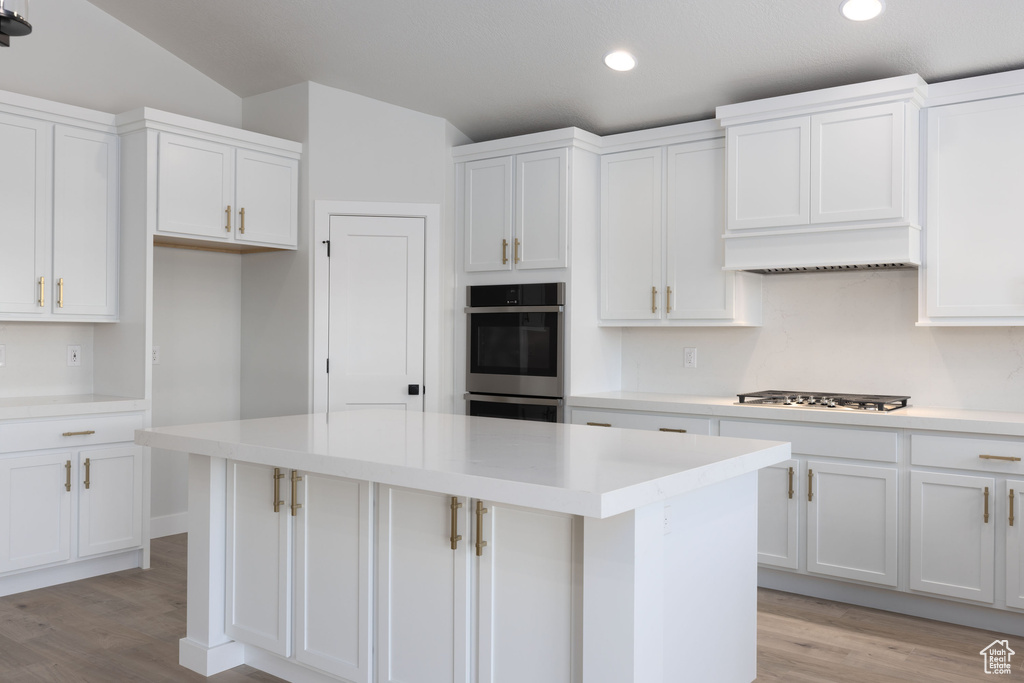 Kitchen with white cabinets, light hardwood / wood-style floors, appliances with stainless steel finishes, and a center island
