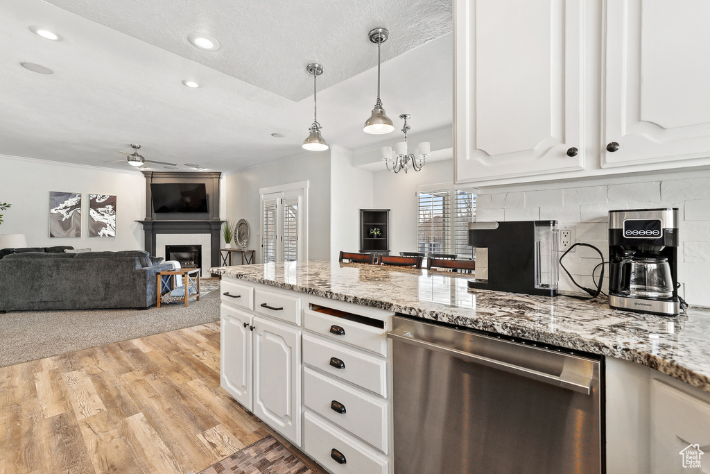 Kitchen featuring white cabinetry, stainless steel dishwasher, light stone countertops, light wood-type flooring, and ceiling fan with notable chandelier