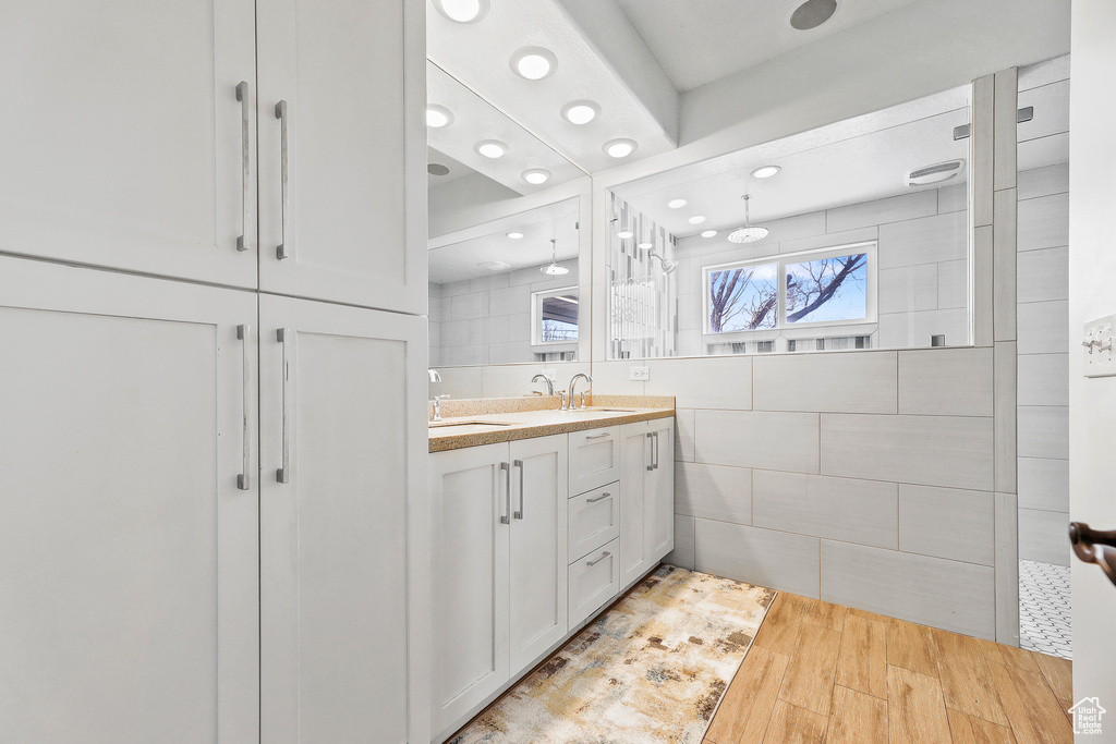 Bathroom featuring tile walls, dual vanity, and hardwood / wood-style floors