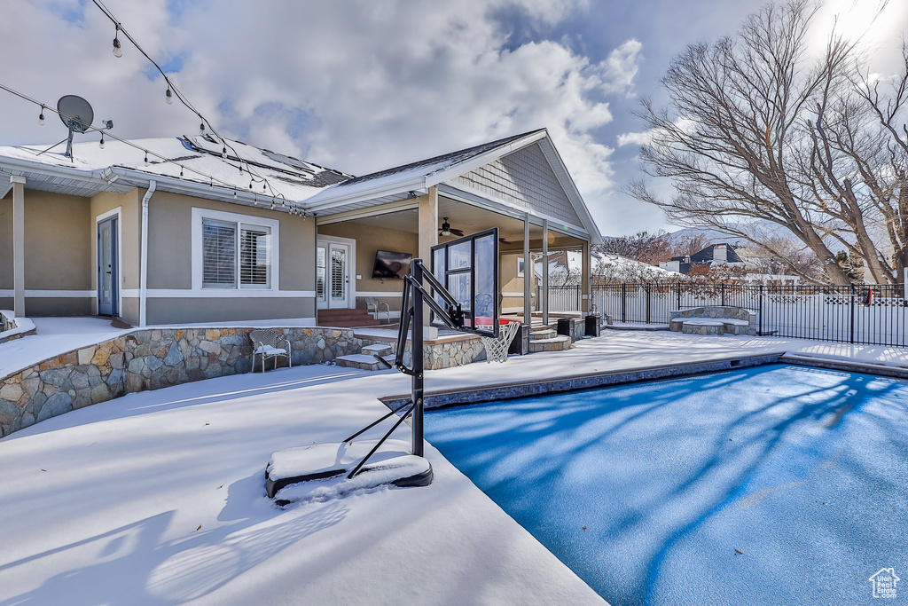 Snow covered pool with a sunroom and a patio area