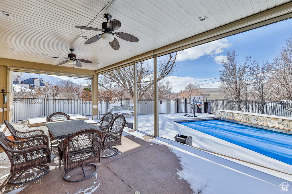 Snow covered patio with a swimming pool and ceiling fan