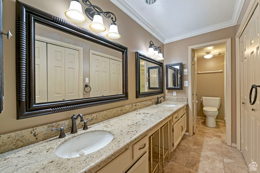 Bathroom with crown molding, tile flooring, double vanity, and toilet