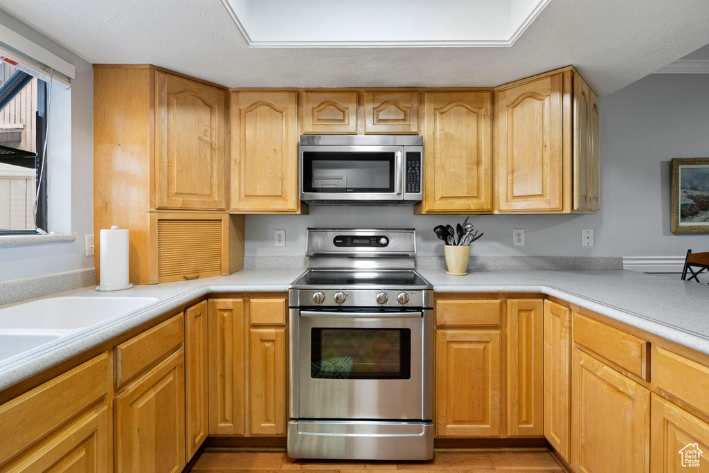 Kitchen with appliances with stainless steel finishes, light brown cabinetry, and light wood-type flooring