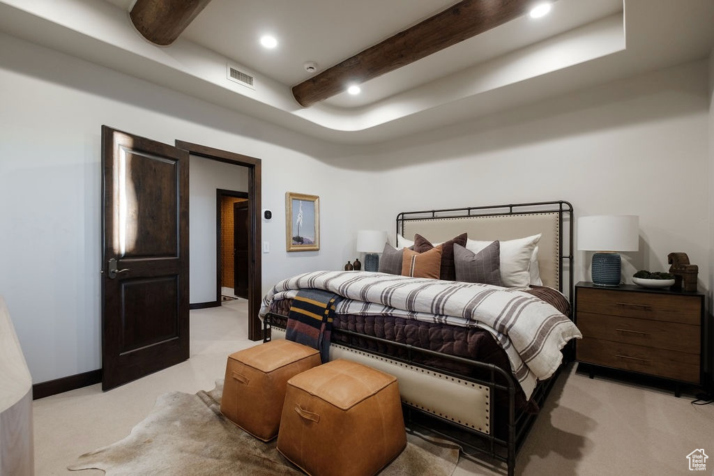 Bedroom with light colored carpet, a tray ceiling, and beam ceiling