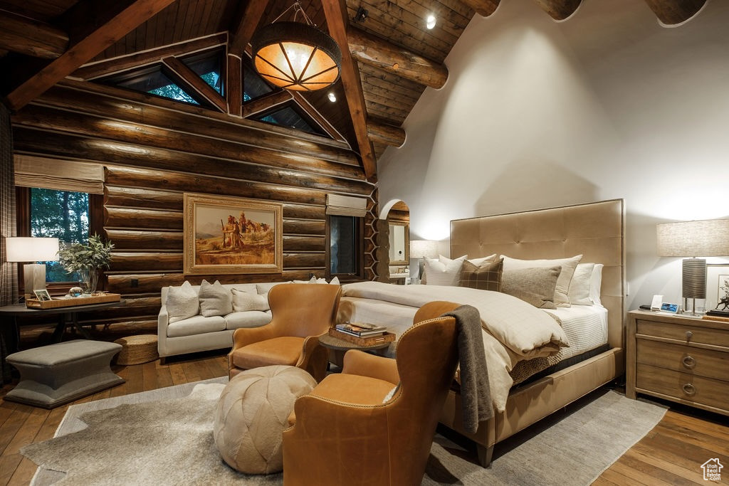 Bedroom featuring beamed ceiling, hardwood / wood-style flooring, and rustic walls