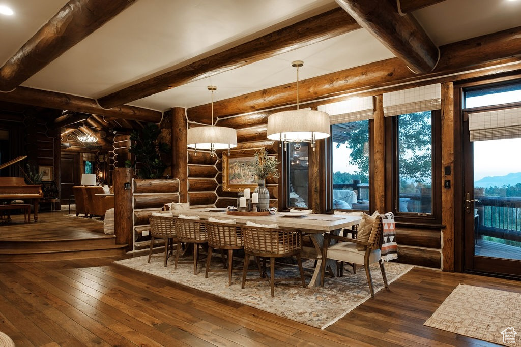 Dining space with beam ceiling, hardwood / wood-style floors, and rustic walls