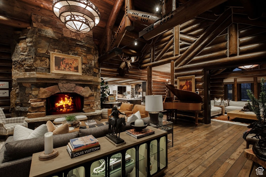 Living room featuring rustic walls, dark hardwood / wood-style flooring, a stone fireplace, and high vaulted ceiling