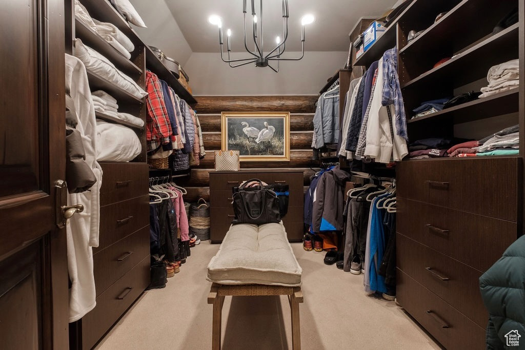 Walk in closet with light carpet and a chandelier