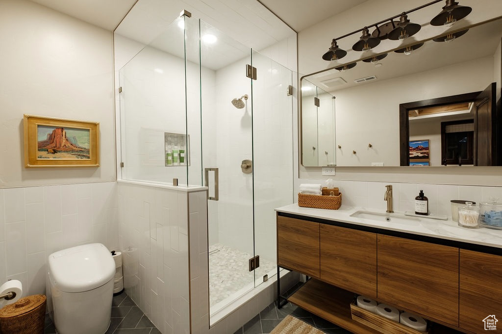 Bathroom with vanity, a shower with door, tile patterned flooring, and tile walls