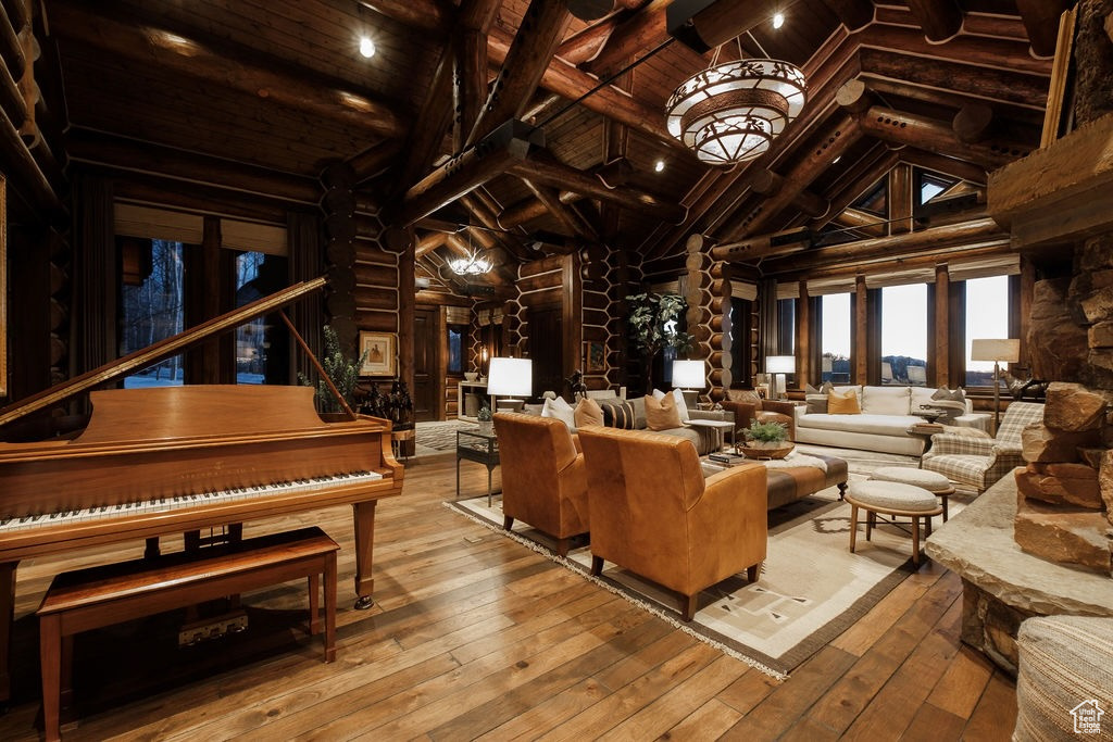 Interior space with light hardwood / wood-style floors, log walls, wood ceiling, high vaulted ceiling, and beamed ceiling