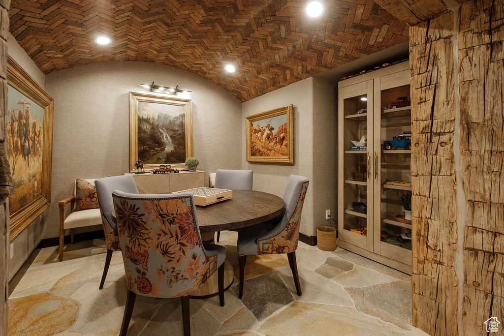 Dining room with brick ceiling, lofted ceiling, and light colored carpet