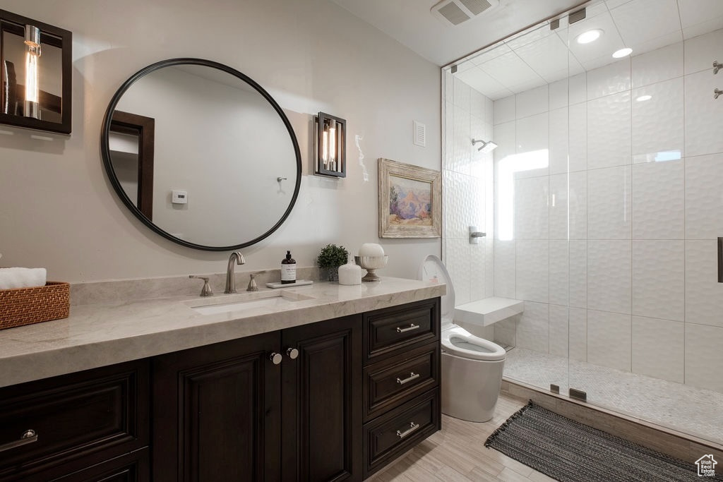 Bathroom featuring a shower with door, vanity, and hardwood / wood-style floors