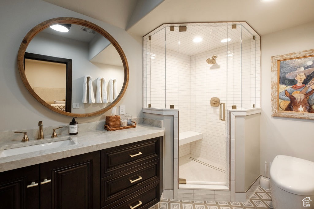 Bathroom featuring large vanity, toilet, an enclosed shower, and tile flooring