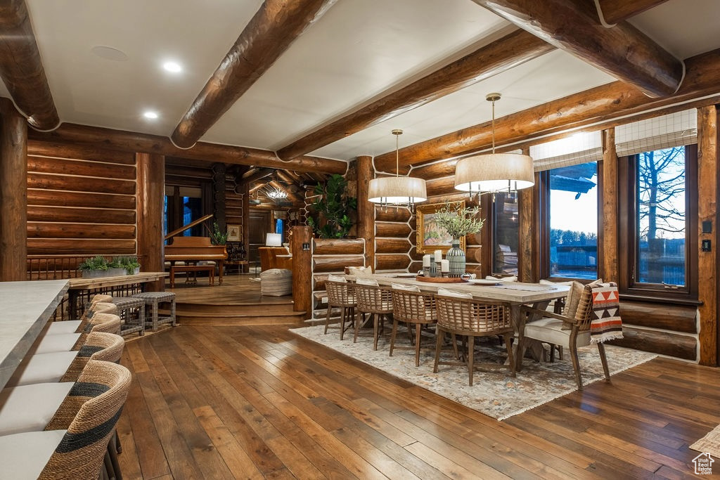 Dining space featuring rustic walls, beamed ceiling, and dark hardwood / wood-style flooring
