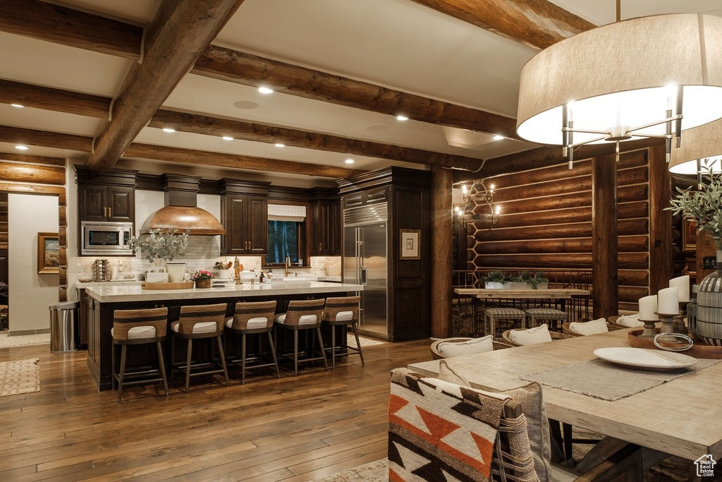 Dining room with beamed ceiling, wood-type flooring, and rustic walls