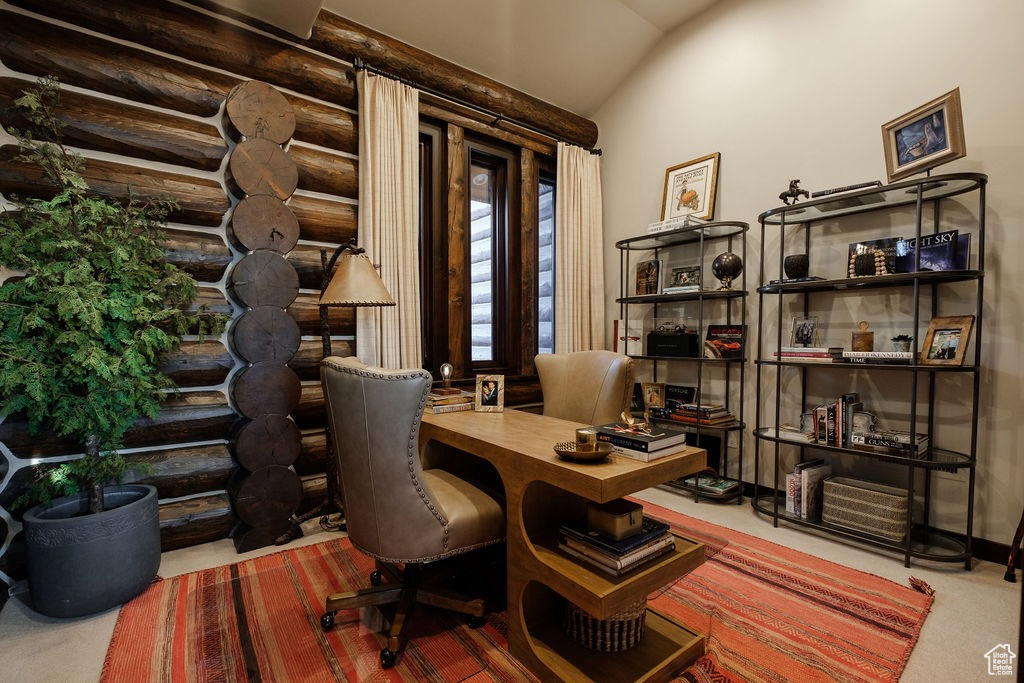 Office featuring rustic walls, carpet flooring, and vaulted ceiling