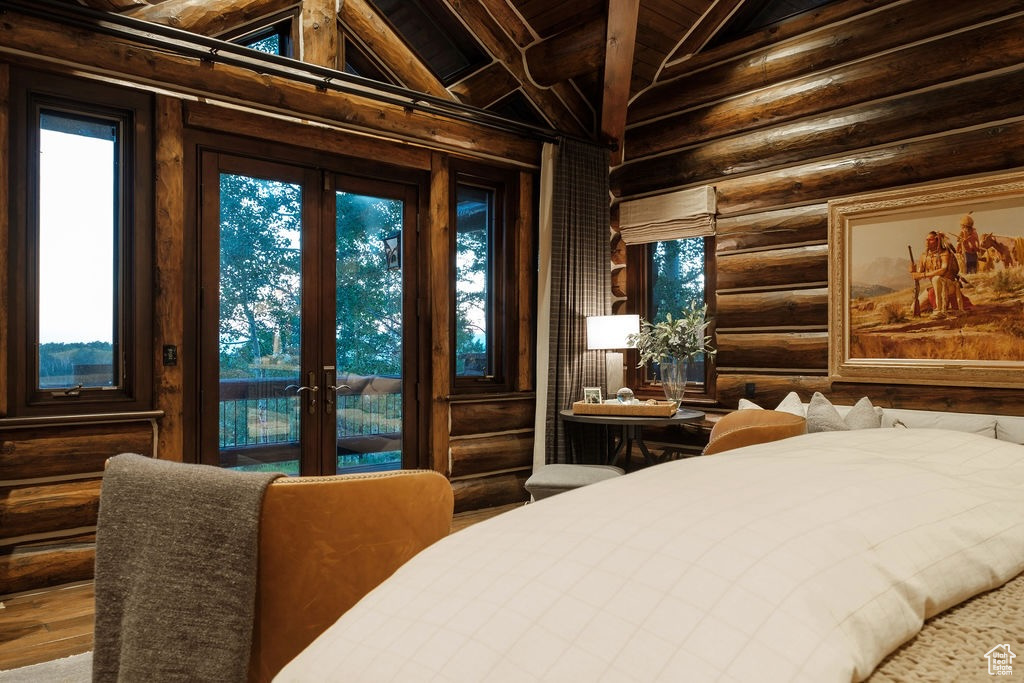 Bedroom with vaulted ceiling with beams, log walls, wood ceiling, french doors, and wood-type flooring