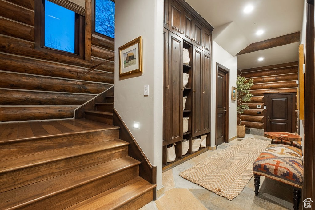 Stairs featuring rustic walls and light colored carpet
