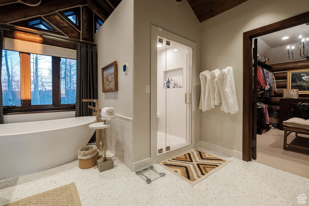 Bathroom featuring shower with separate bathtub and lofted ceiling