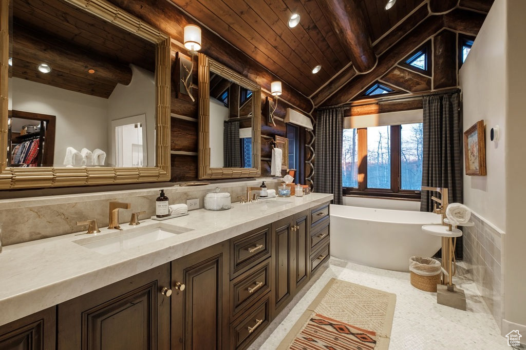 Bathroom featuring a tub, dual vanity, lofted ceiling with beams, tile floors, and wood ceiling