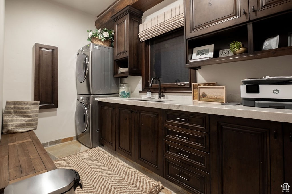 Kitchen with sink, light hardwood / wood-style flooring, stacked washing maching and dryer, and dark brown cabinets