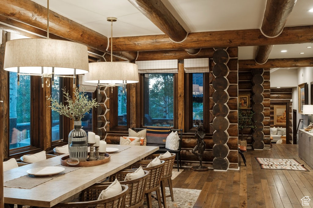 Dining room featuring beamed ceiling, wood-type flooring, and rustic walls