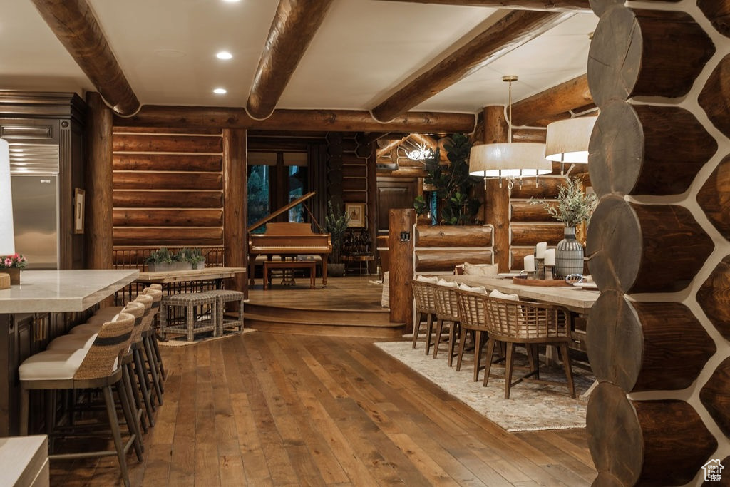 Dining area with beam ceiling, rustic walls, and hardwood / wood-style floors