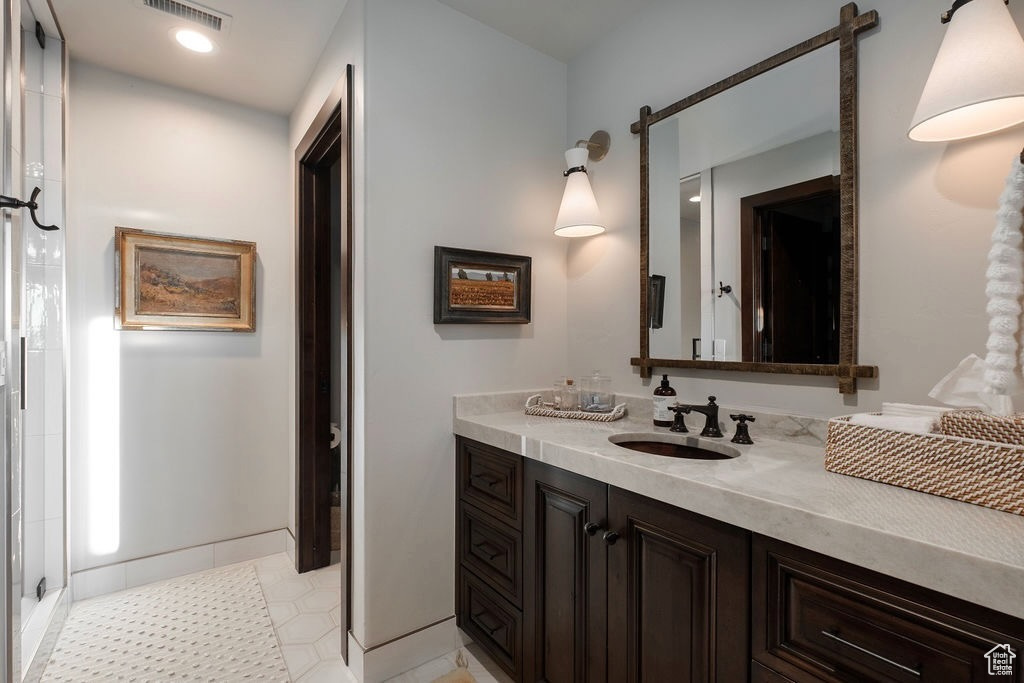 Bathroom featuring vanity, walk in shower, and tile patterned flooring