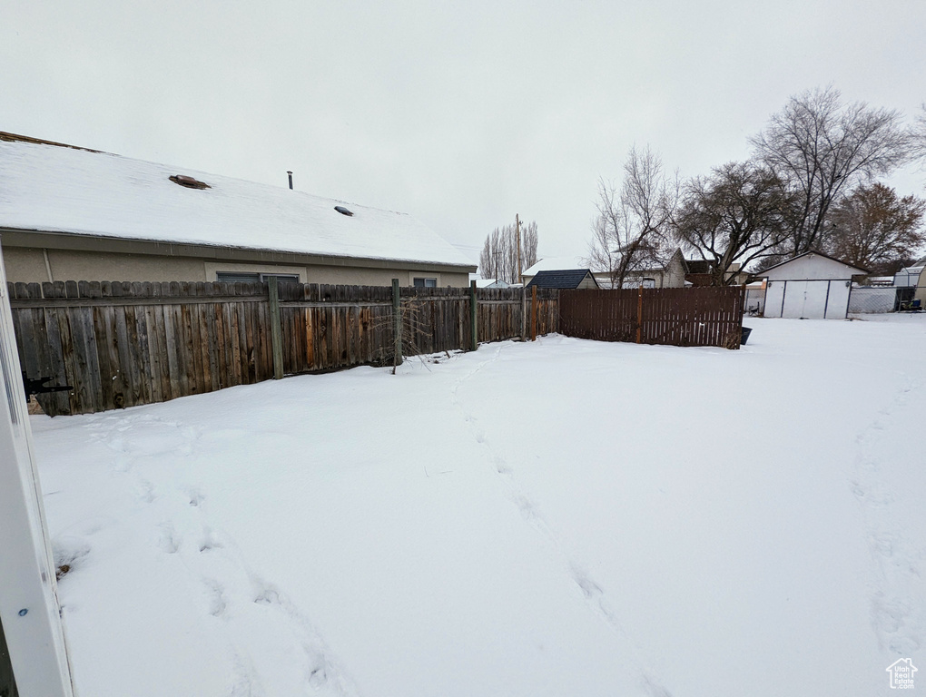 Yard covered in snow featuring a shed